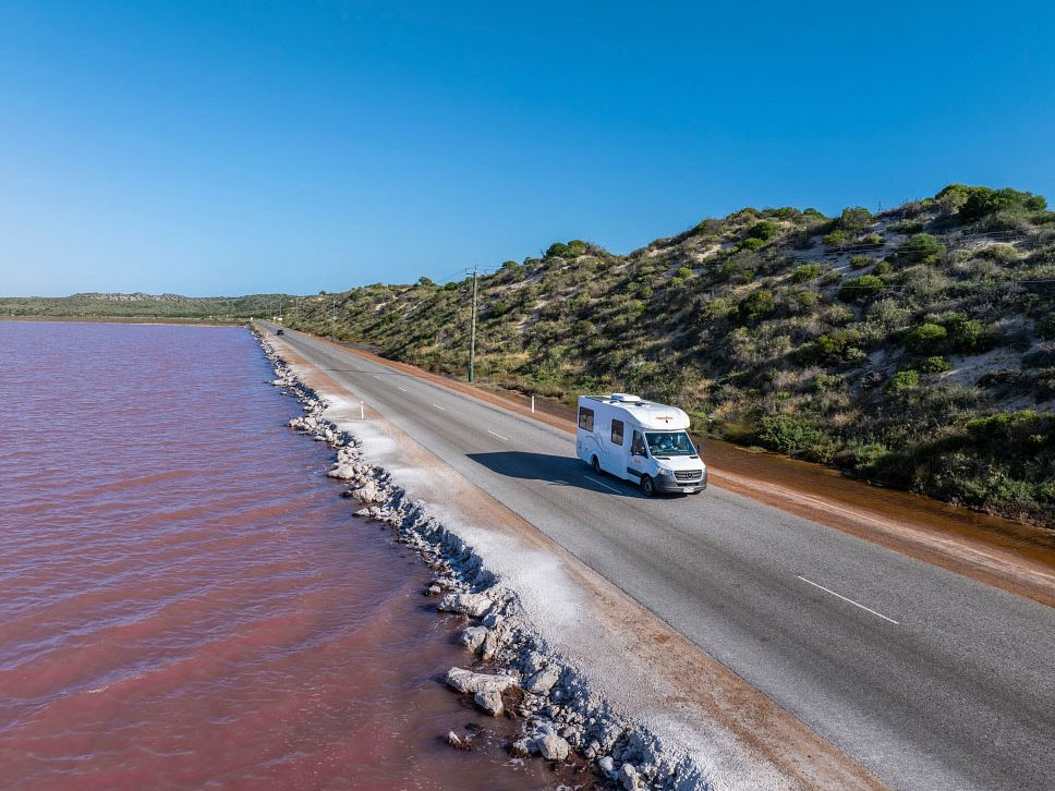 Apollo Euro Quest motorhome hire in Australia beside a pink salt lake on a scenic coastal road in WA