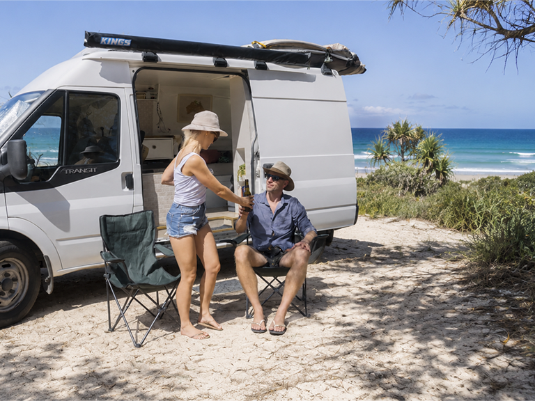 Couple relaxing beside a campervan hire on Minjerribah (North Stradbroke Island) near Brisbane