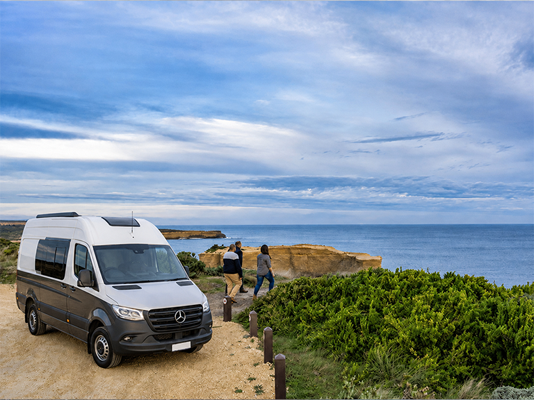 Travellers stopping beside their campervan at a coastal viewpoint on the Great Ocean Road