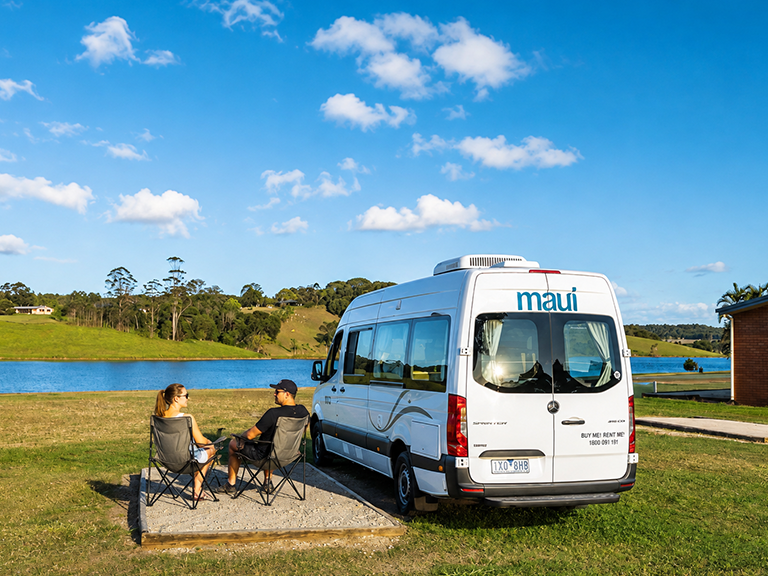 Couple relaxing beside a Maui campervan near a tropical lagoon in Cairns