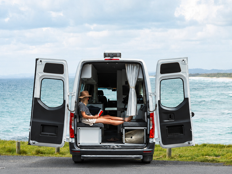 Traveller relaxing inside a motorhome rental overlooking the coast near Byron Bay