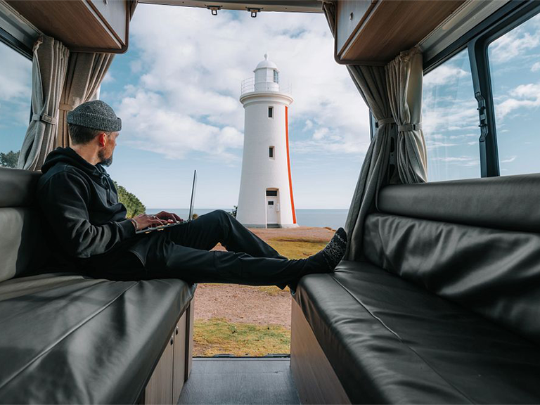 Traveller relaxing inside a motorhome rental overlooking Mersey Bluff Lighthouse in Devonport
