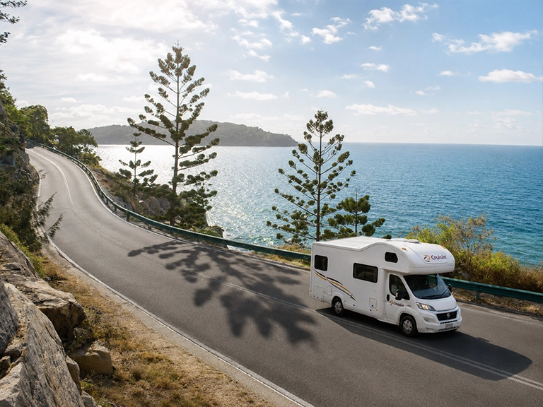 Motorhome rental driving along a coastal road near Townsville