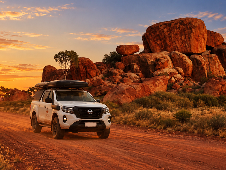 4WD campervan hire vehicle driving past Karlu Karlu Devils Marbles at sunset in the Northern Territory