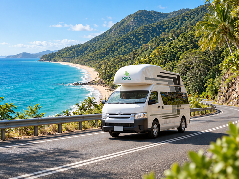 Kea campervan rental travelling along the Captain Cook Highway beside the tropical coast in Far North Queensland