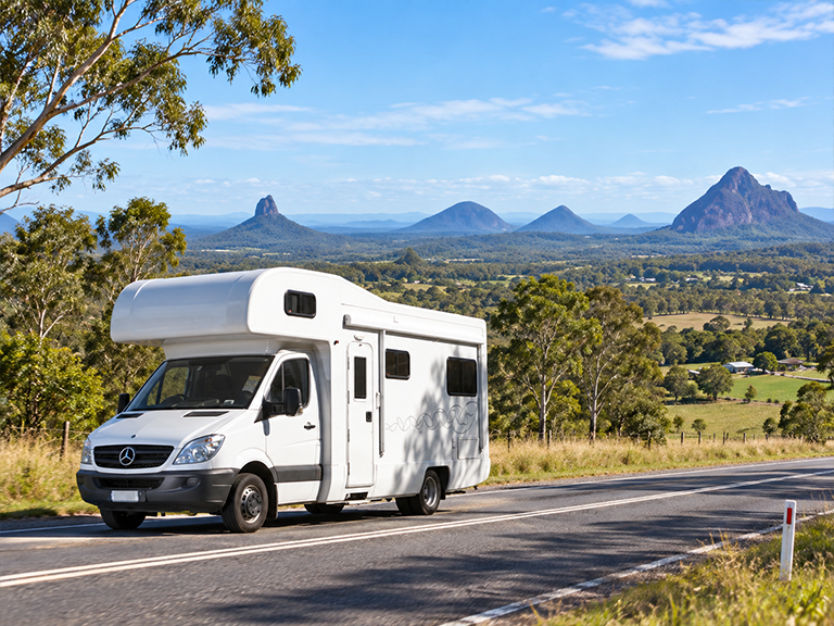 Motorhome vehicle driving with the Glass House Mountains in the background in Queensland